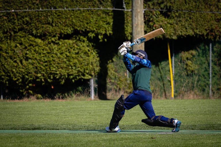 Playing 11 today powerful shot during a cricket match on a sunny day.