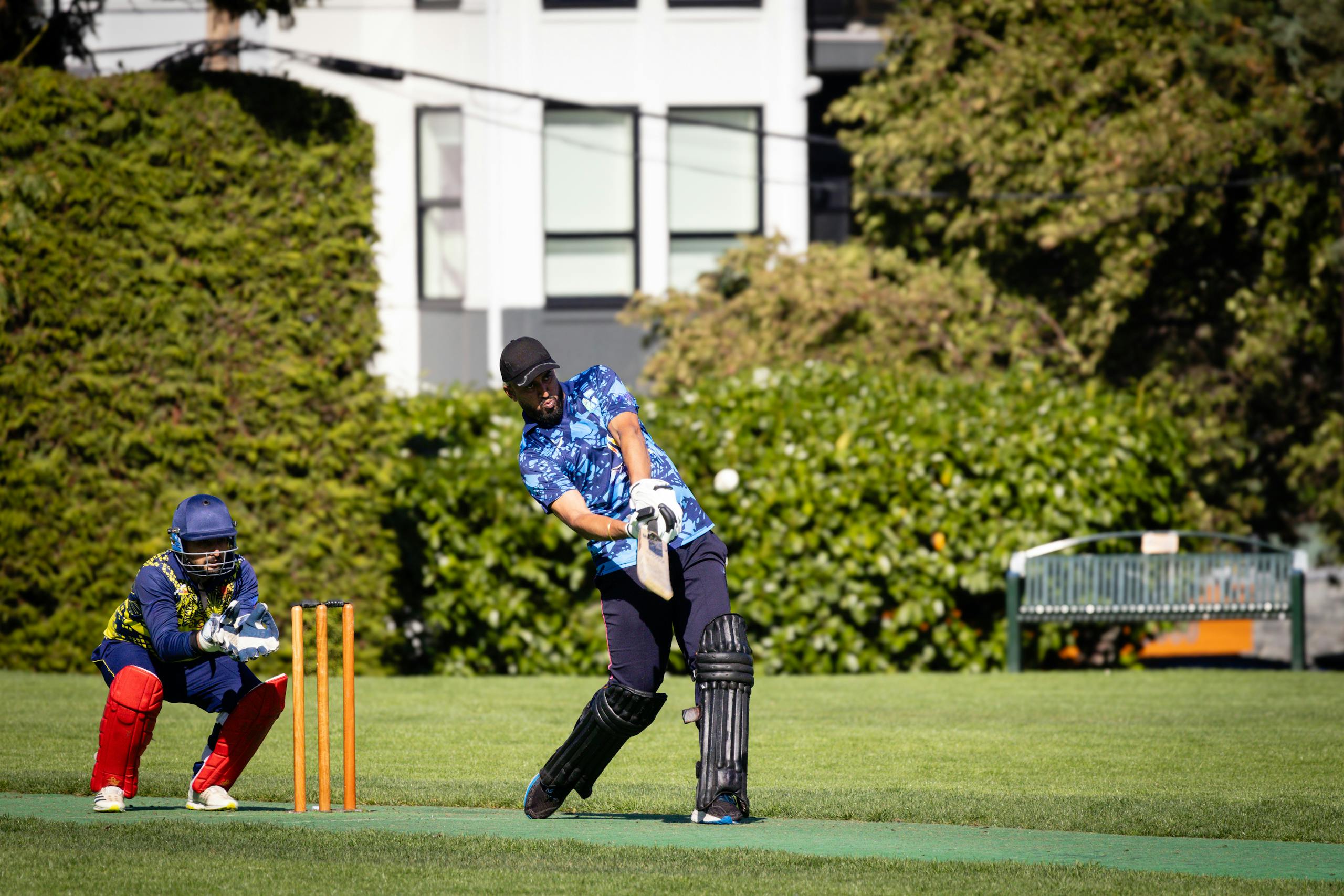 IPL live score shot of a cricket batsman hitting the ball during an outdoor match.