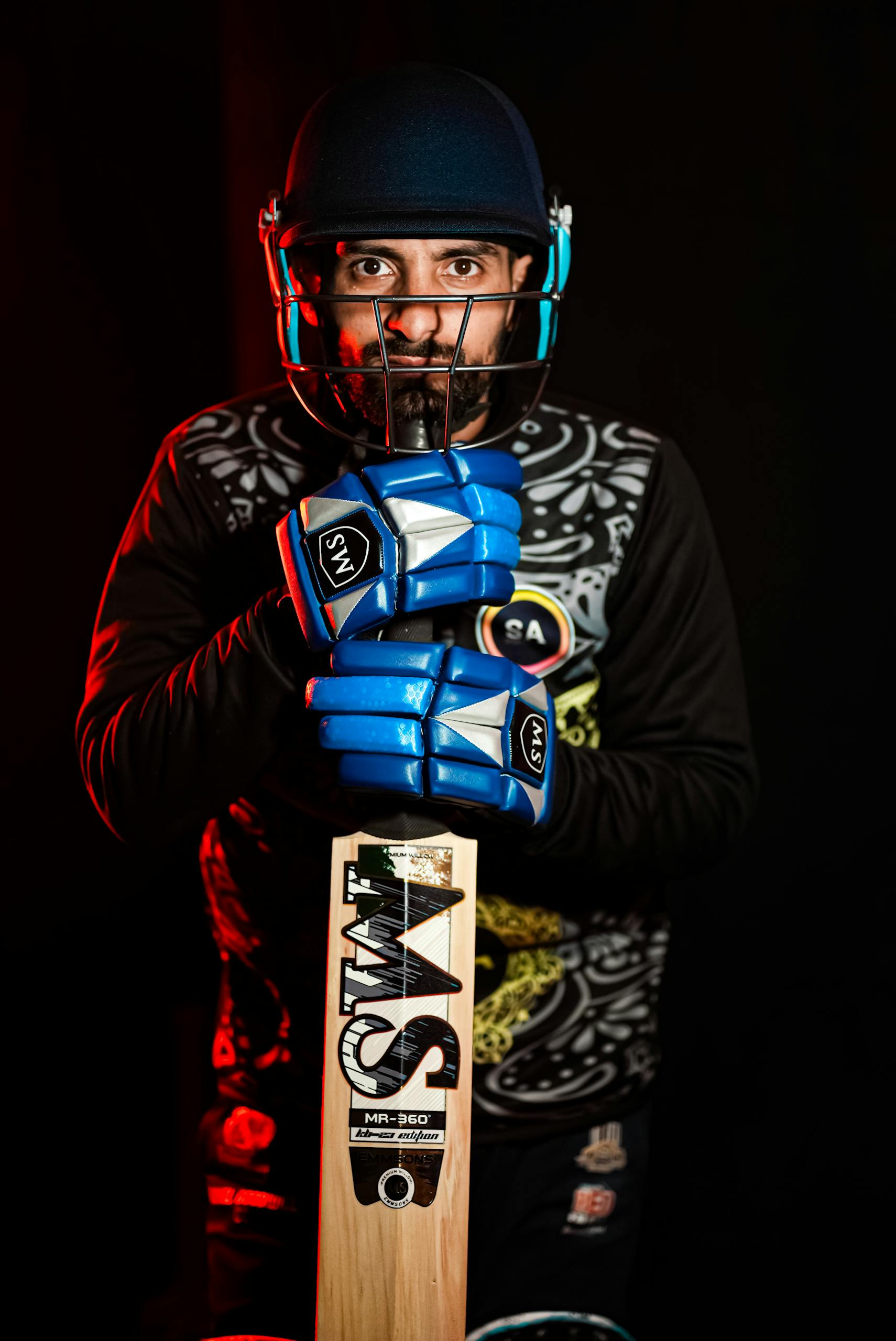 IPL points table prediction cricketer in helmet and gloves holding a cricket bat in a studio setting.