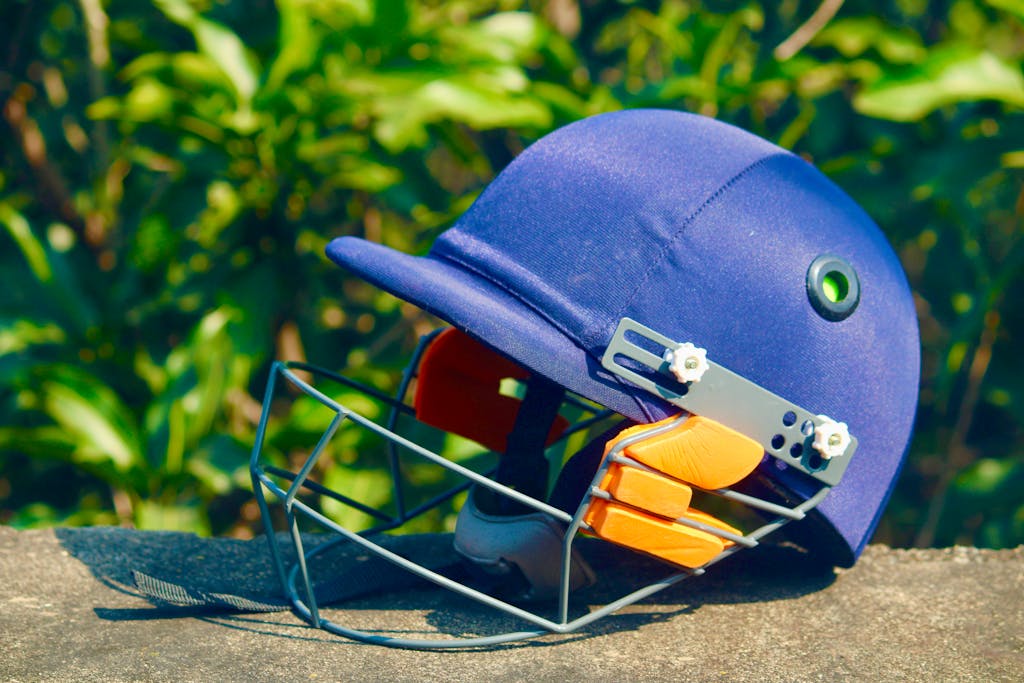 IPL points table helmet placed on a stone surface with green foliage background, shot outdoors.
