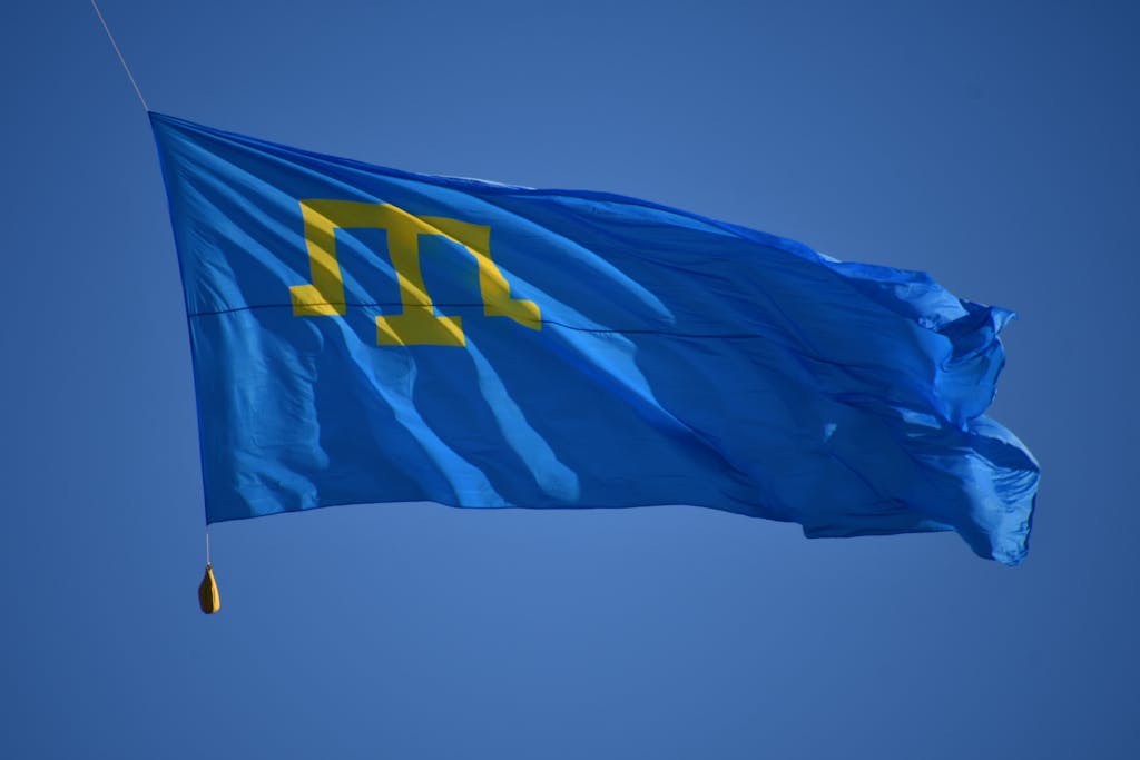TaTa IPL Vibrant Crimean Tatar flag waving against a clear blue sky in Kiev, symbolizing freedom and identity.