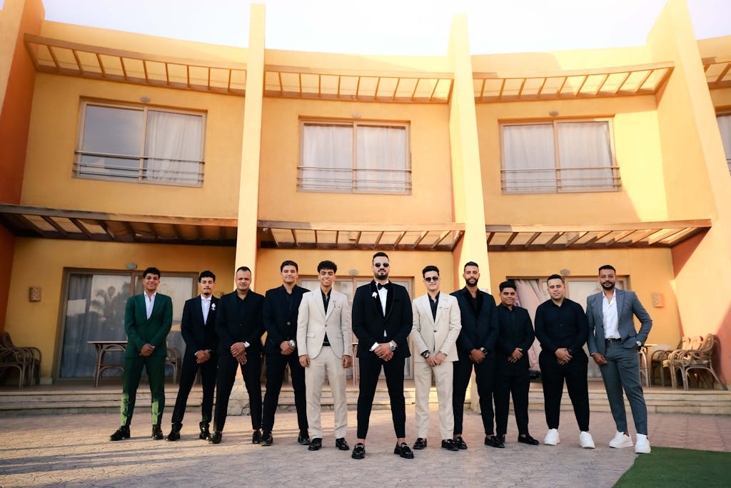 RCB Squad 2026 A group of men in formal attire stands in front of a modern building facade.