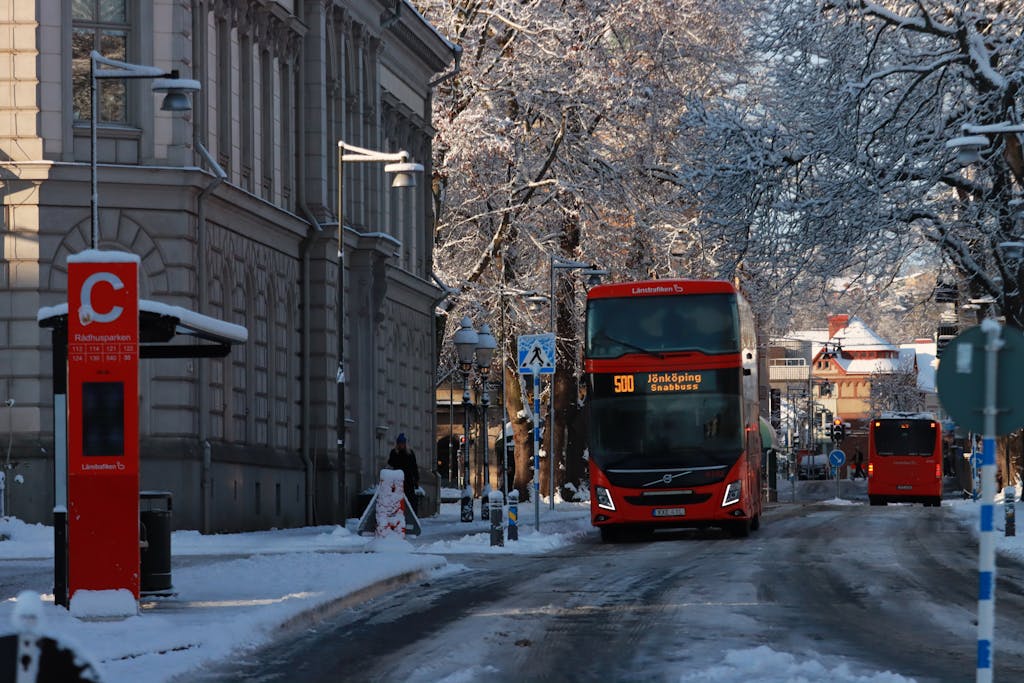circkbuss com A red double-decker bus driving through a snowy street in Jönköping, Sweden.