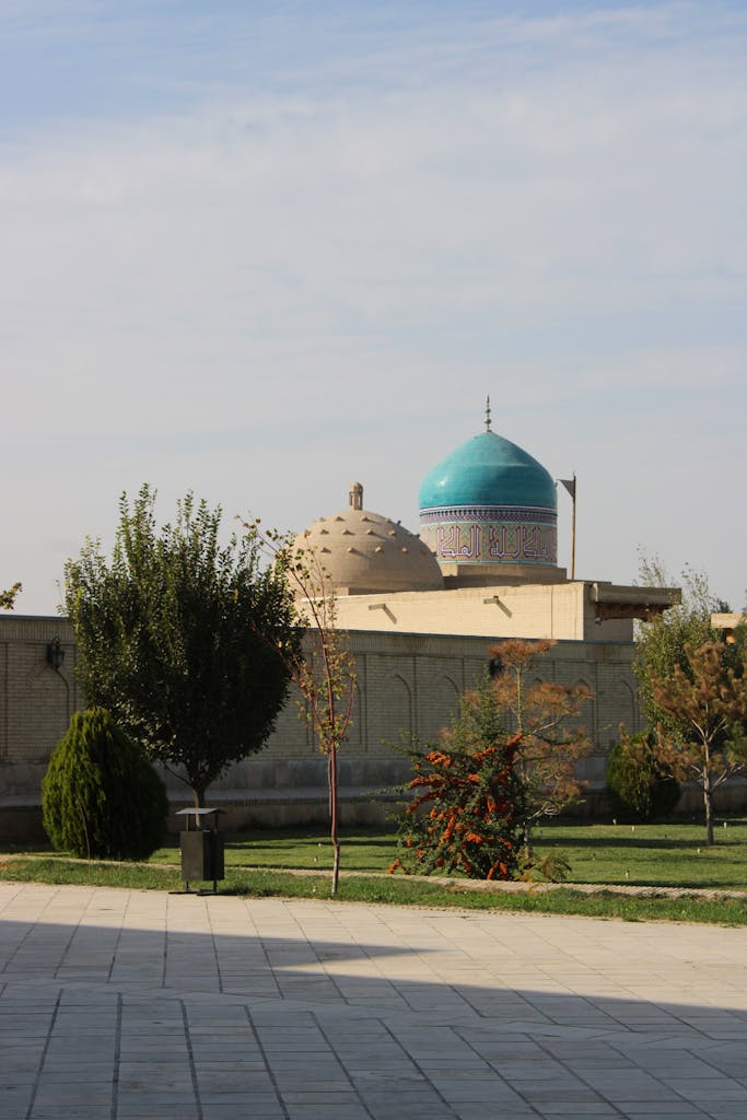 Voozon A stunning mosque with a blue dome towers over lush gardens, basking under a clear sky.
