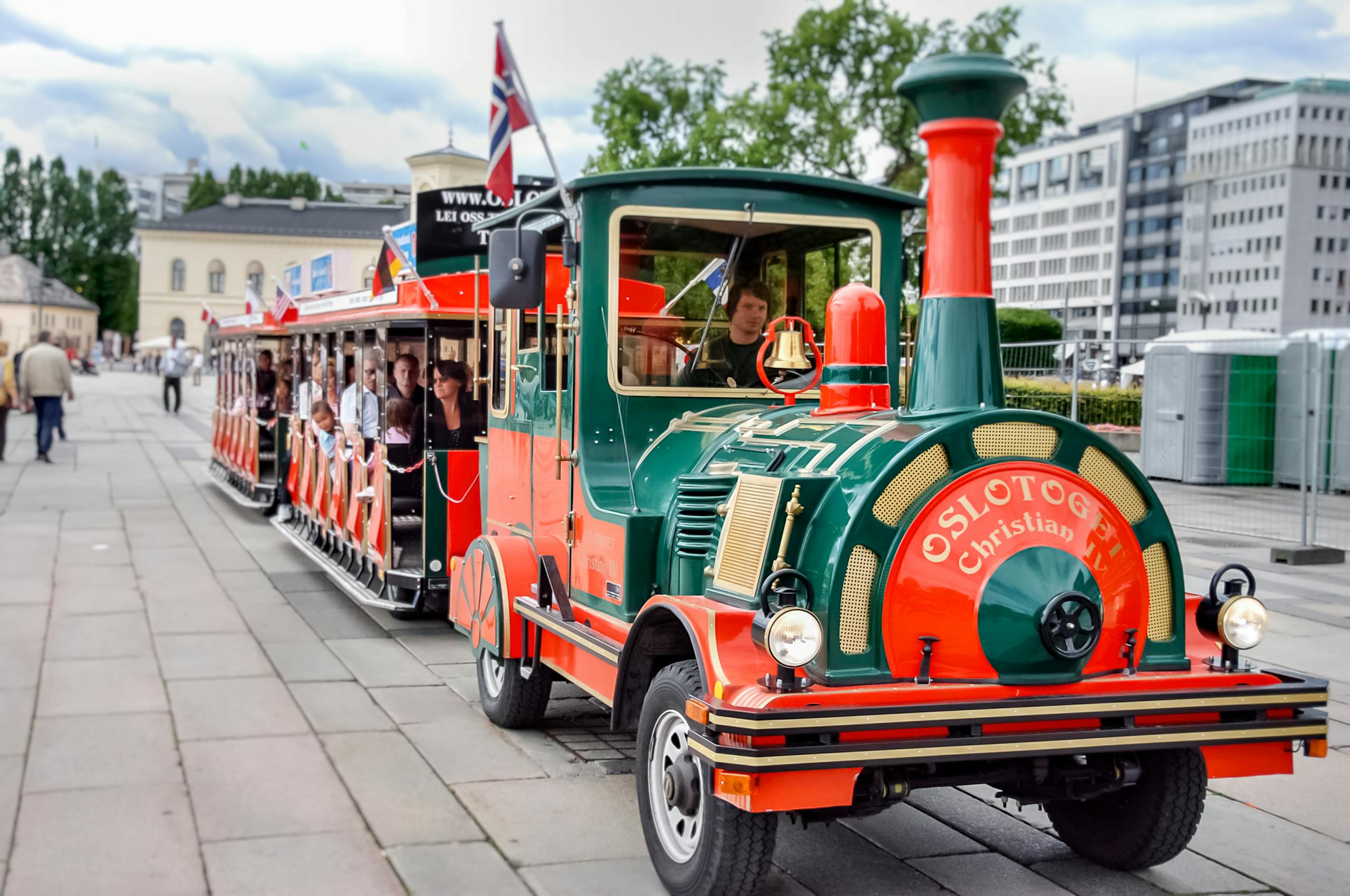 circkbuss com A vibrant trackless train touring the streets of Oslo, offering scenic views with passengers enjoying the ride.