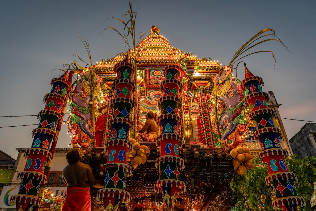 Opening Ceremony 2026 Beautifully illuminated festival chariot with intricate designs during a Hindu celebration at twilight.