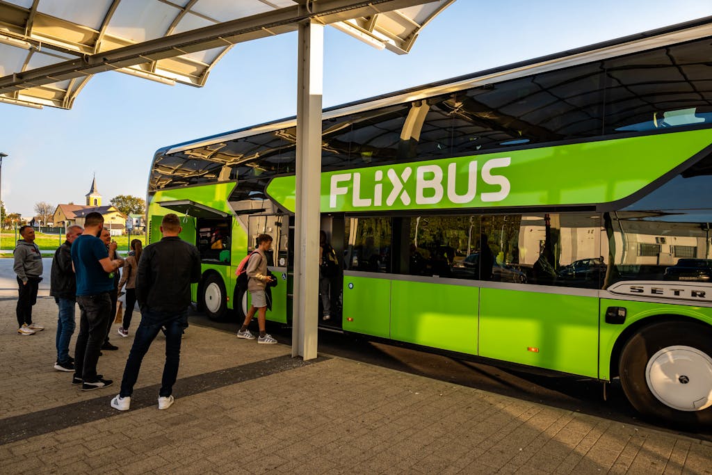circkbuss com Passengers boarding a green Flixbus at Kutina Bus Station on a sunny day in Croatia.
