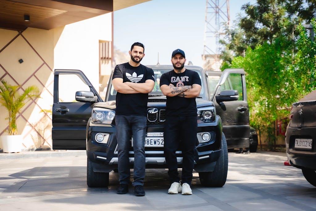 RCB Squad 2026 Two men with crossed arms standing in front of an SUV in urban Jaipur, Rajasthan.