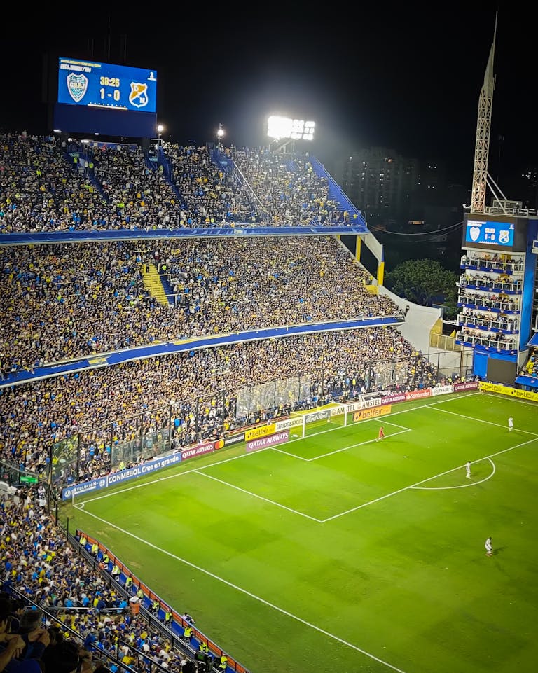 Full Match List Vibrant soccer game at La Bombonera Stadium in Buenos Aires. Enthusiastic fans fill the stands under bright lights.