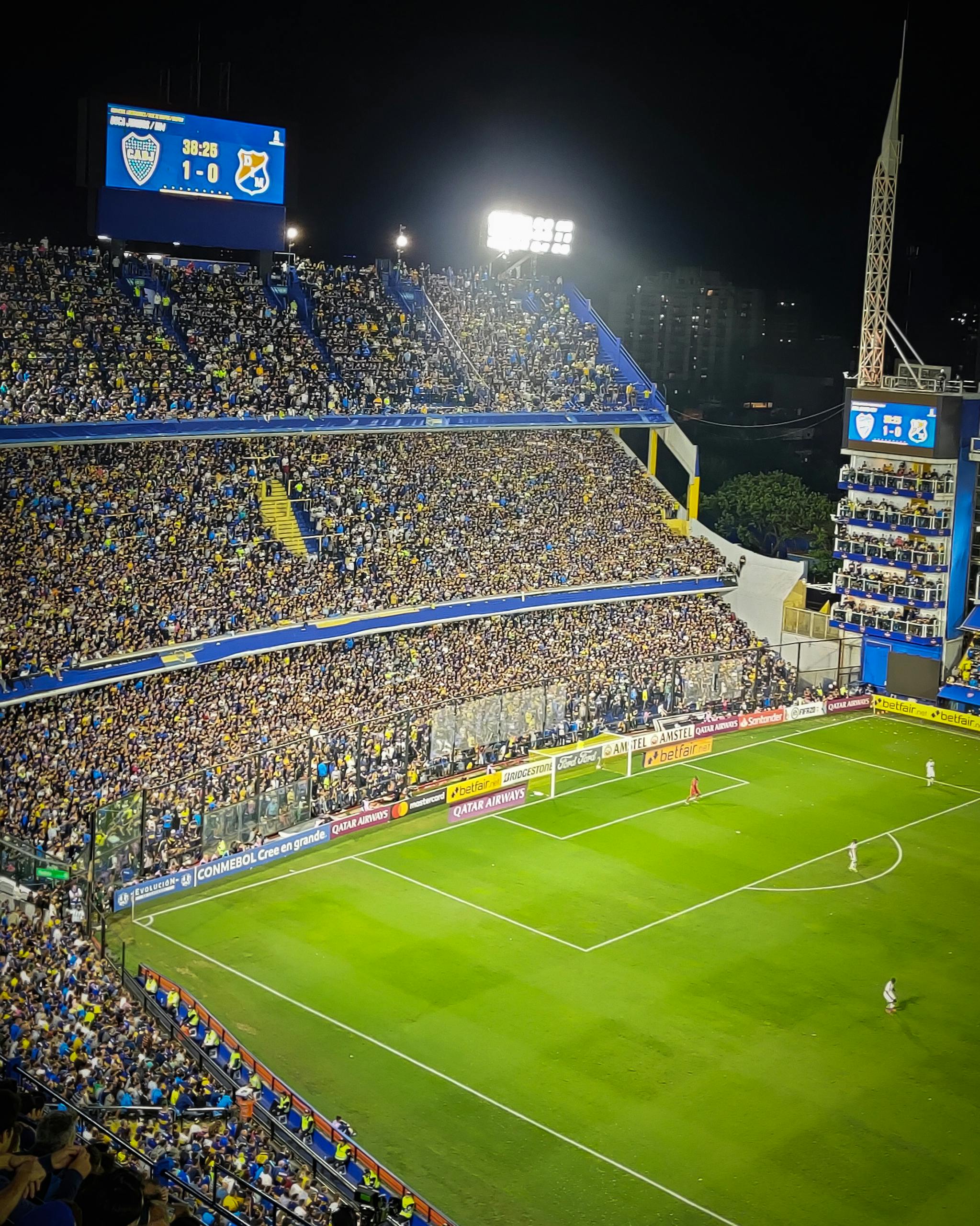 Full Match List Vibrant soccer game at La Bombonera Stadium in Buenos Aires. Enthusiastic fans fill the stands under bright lights.
